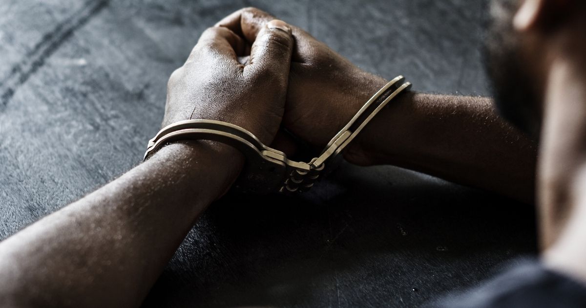 The above stock image shows a man in handcuffs.