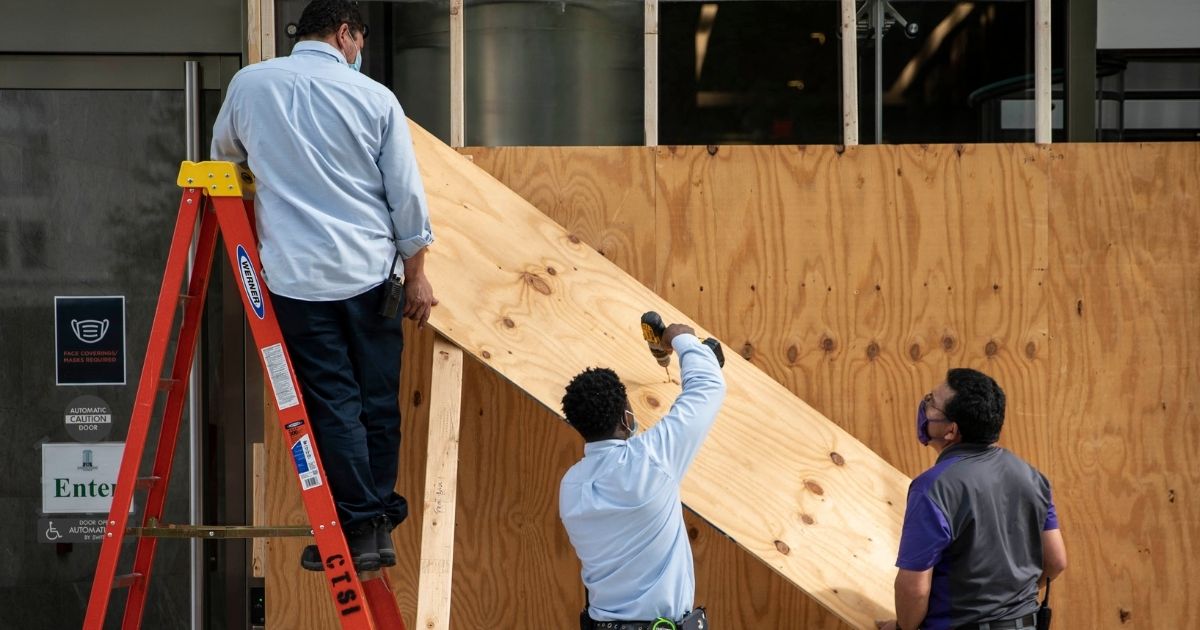 Workers put boards on the windows of a building on Oct. 28, 2020, near the White House in Washington, D.C.