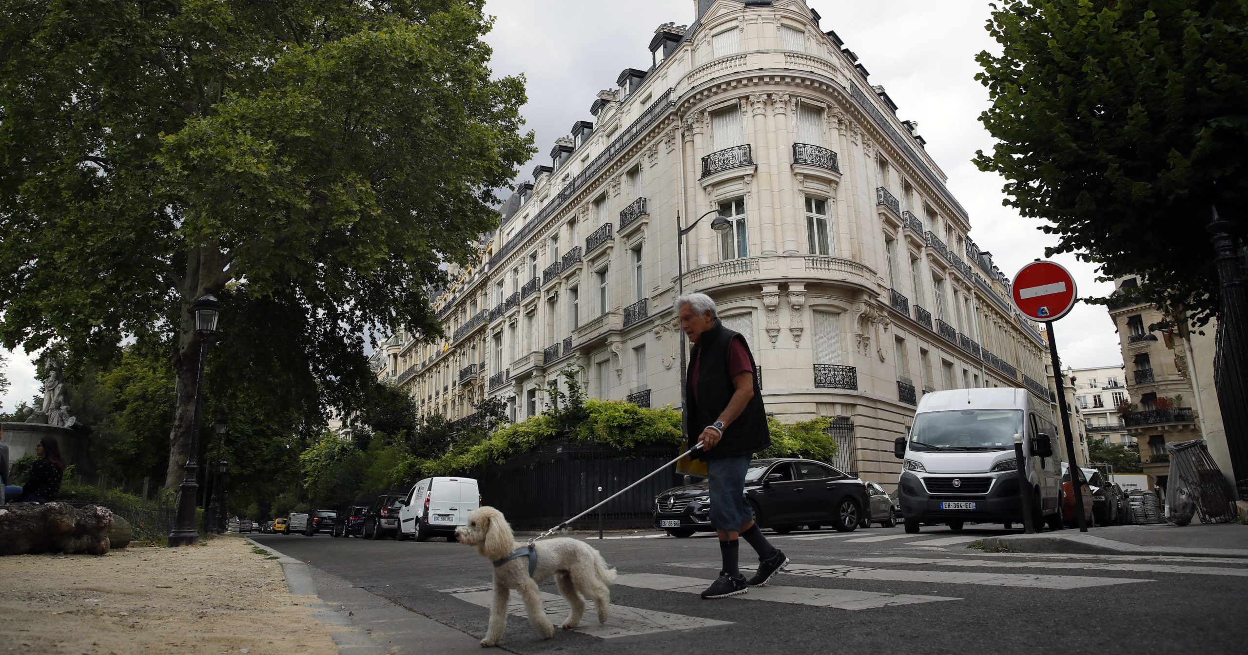 In this Aug.13, 2019, file photo, a man walks his dog next to an apartment building owned by Jeffrey Epstein in Paris.