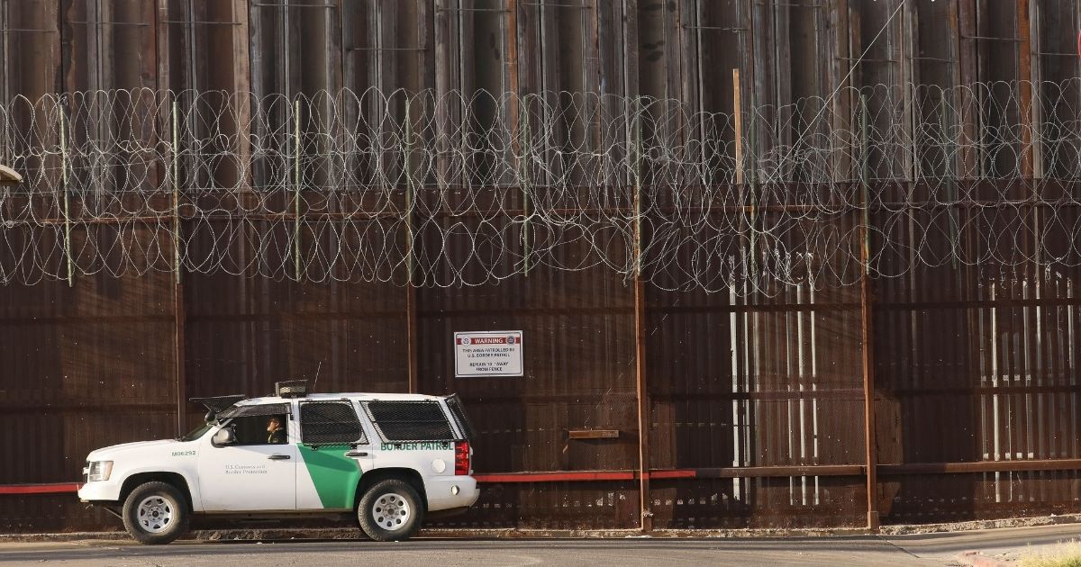A Border Patrol agent is posted in front of the U.S.-Mexico border barrier in Imperial County, which has been hard-hit by the COVID-19 pandemic on July 24 in Calexico, California.