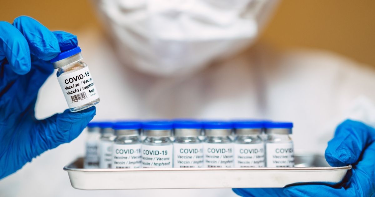 A health care professional holds a tray of COVID-19 vaccines.