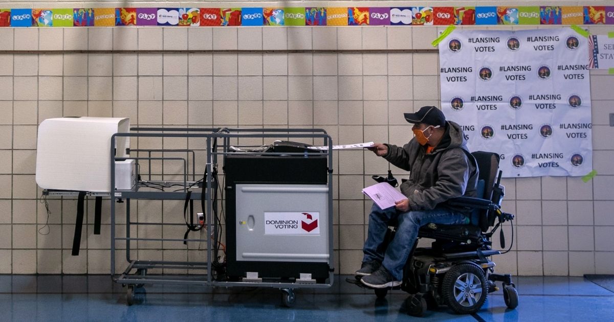 A voter feeds his ballot into a Dominion machine at a school gymnasium in Lansing, Michigan, on Nov. 3.