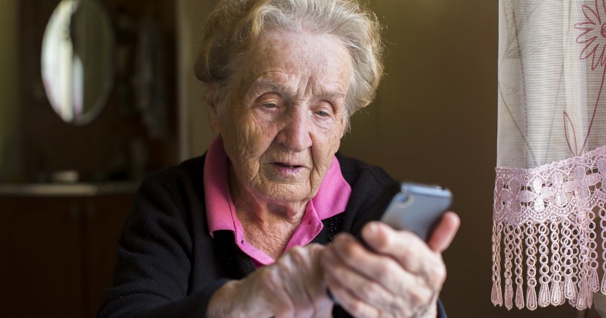 An elderly woman uses a smartphone.