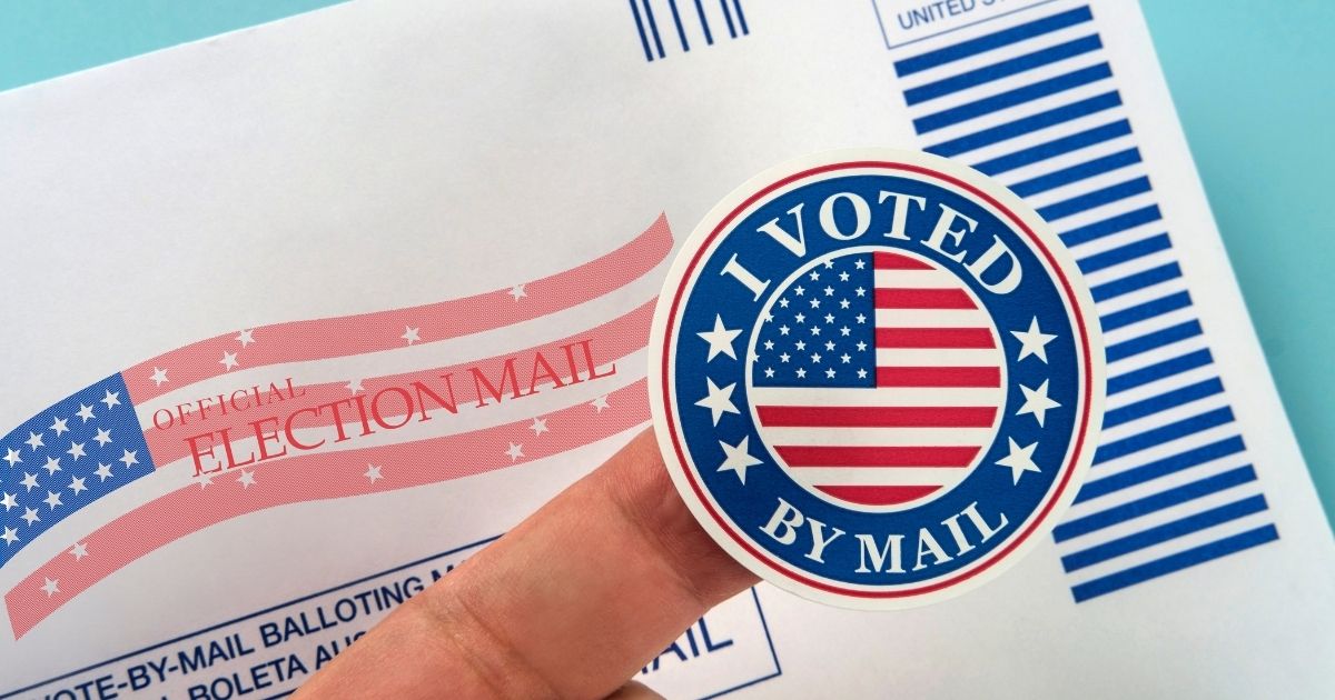 In the stock photo above a person holds a sticker, showing they voted by mail.