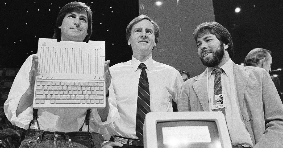 In this April 24, 1984 file photo, Steve Jobs, left, then the chairman of Apple Computers, John Sculley, center, then the president and CEO, and Steve Wozniak, co-founder of Apple, unveil the Apple IIc computer in San Francisco, California.