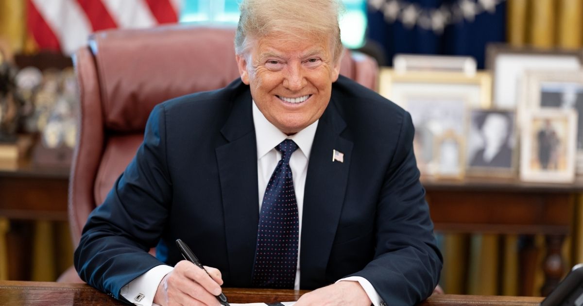 President Donald Trump signs a memorandum in the Oval Office of the White House on June 24.