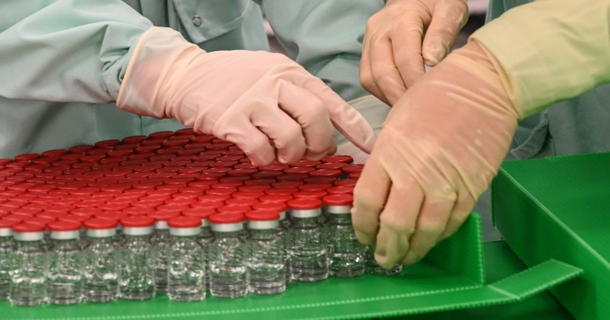 Laboratory tecnicians handle capped vials of a potential COVID-19 vaccine at a facility in Anagni, Italy.