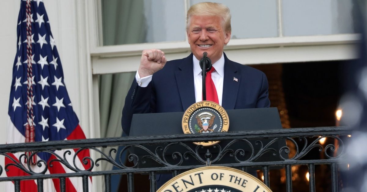A grinning President Donald Trump pumps a fist at supporters in a file photo from May 22.