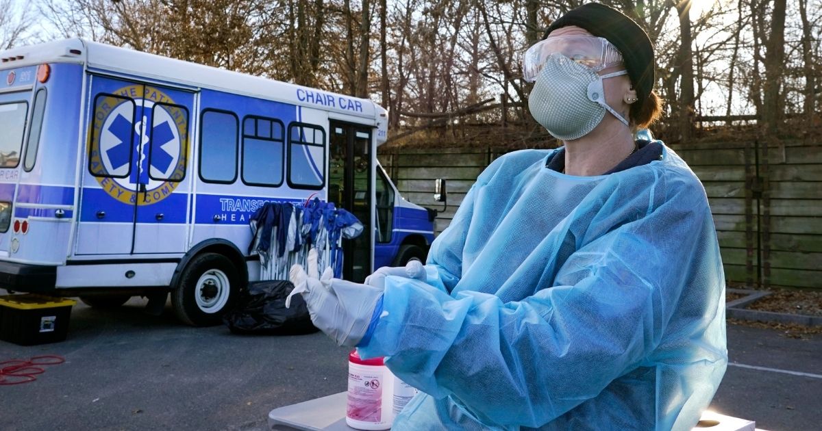 An emergency medical technician dons gloves to administer COVID-19 testing recently in Lawrence, Massachusetts.
