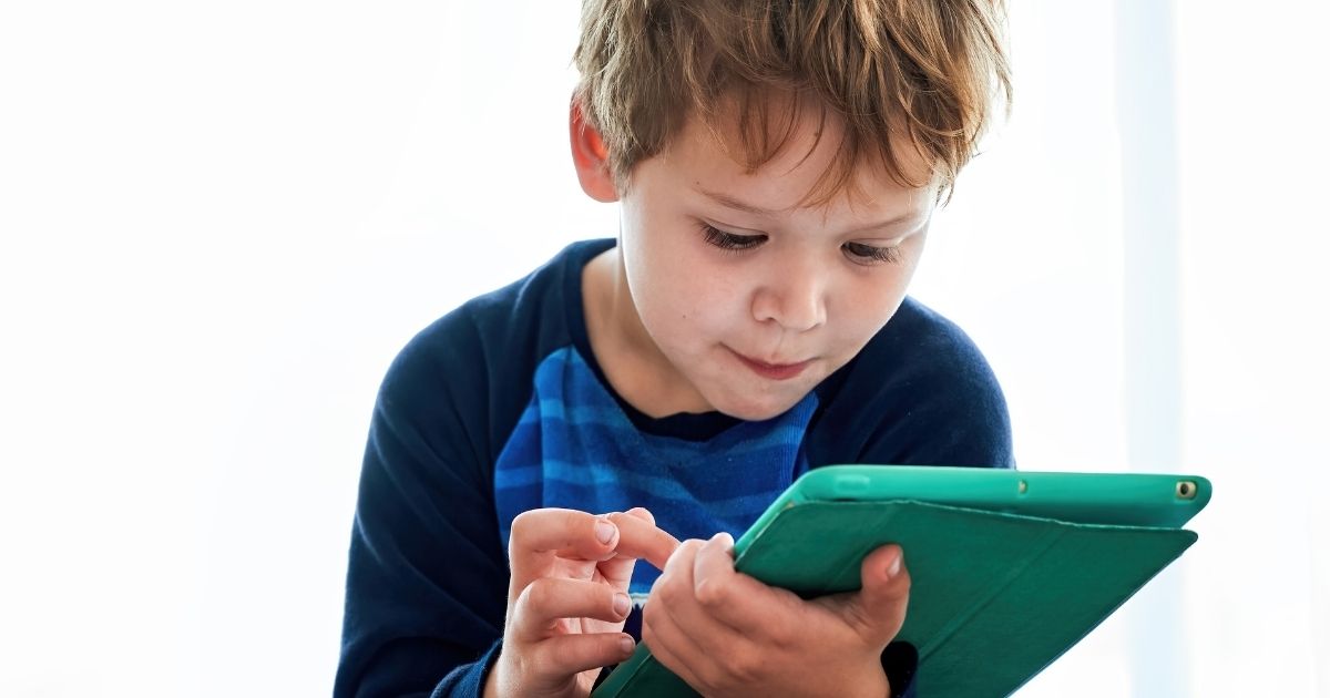 A little boy plays with an iPad in the above stock photo.
