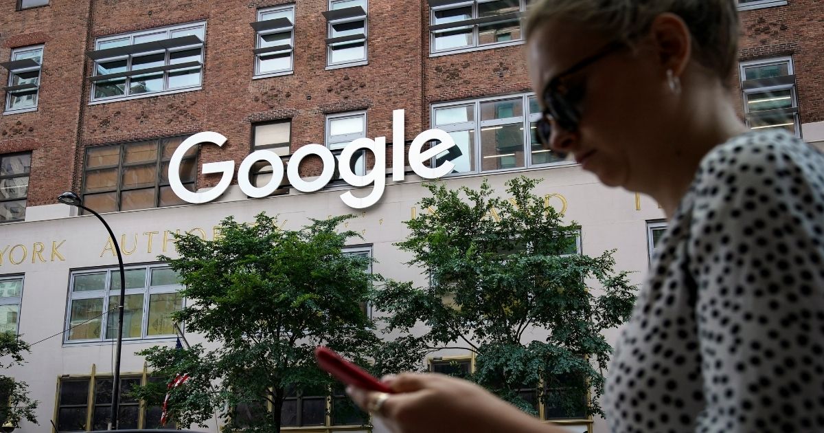 A woman looks at her smartphone as she walks past a Google building on June 3, 2019, in New York City.
