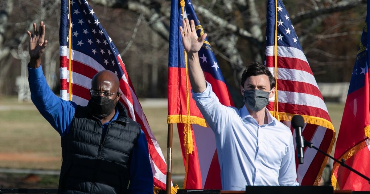Democratic US Senate candidates Raphael Warnock, left, and Jon Ossoff wave to the crowd during a rally on Dec. 5, 2020, in Conyers, Georgia.