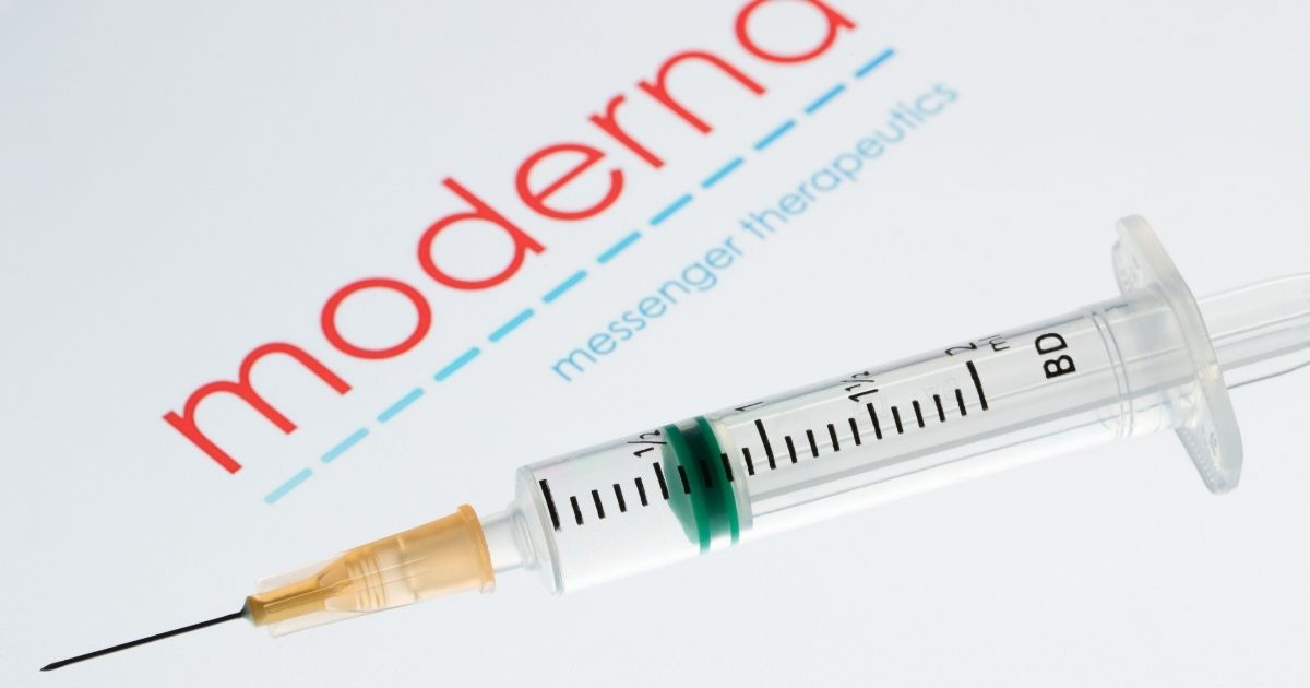 This picture taken on Nov. 18, 2020, shows a syringe next to the Moderna company logo.
