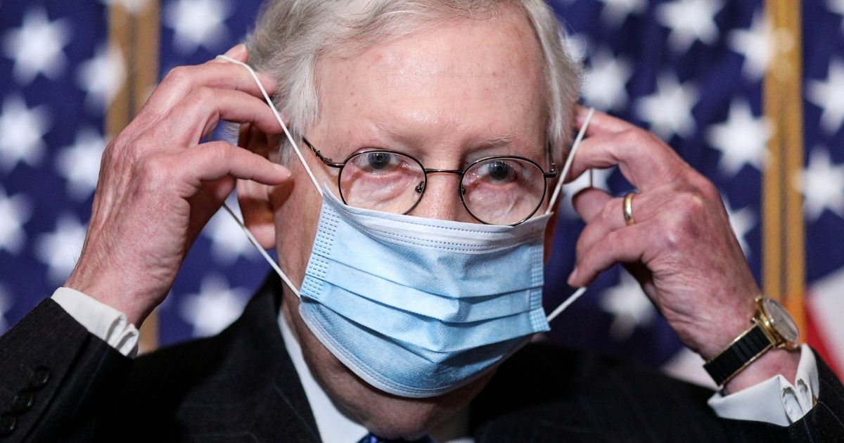 Senate Majority Leader Mitch McConnell removes his face mask as he arrives for a news conference at the US Capitol on Dec. 15, 2020, in Washington, D.C.