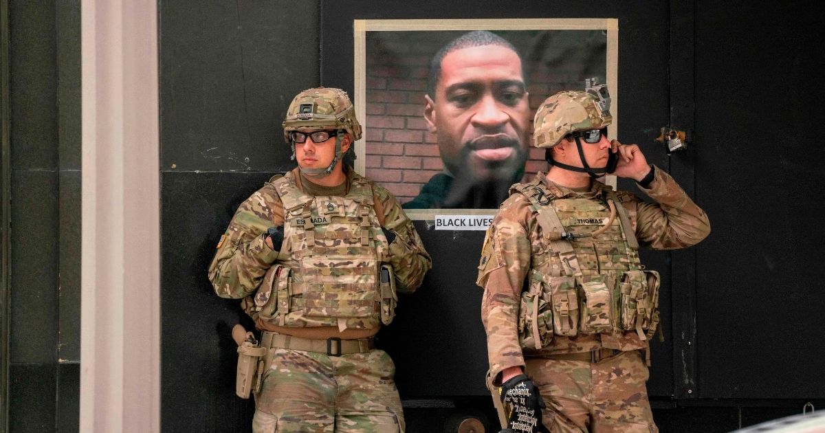 California National Guardsmen stand near a portrait of George Floyd during a demonstration in downtown Los Angeles on June 6, 2020.