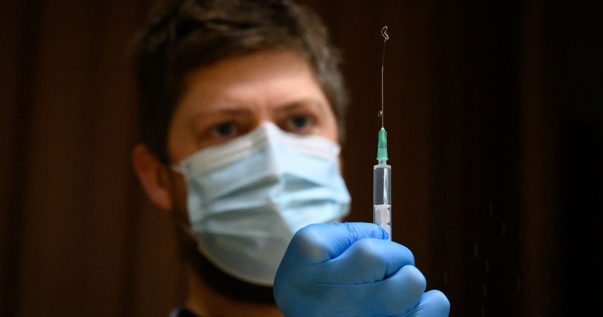 A paramedic flushes a syringe before preparing a shot of the Pfizer-BioNTech COVID-19 vaccine on Dec. 16, 2020, in Chertsey, England.