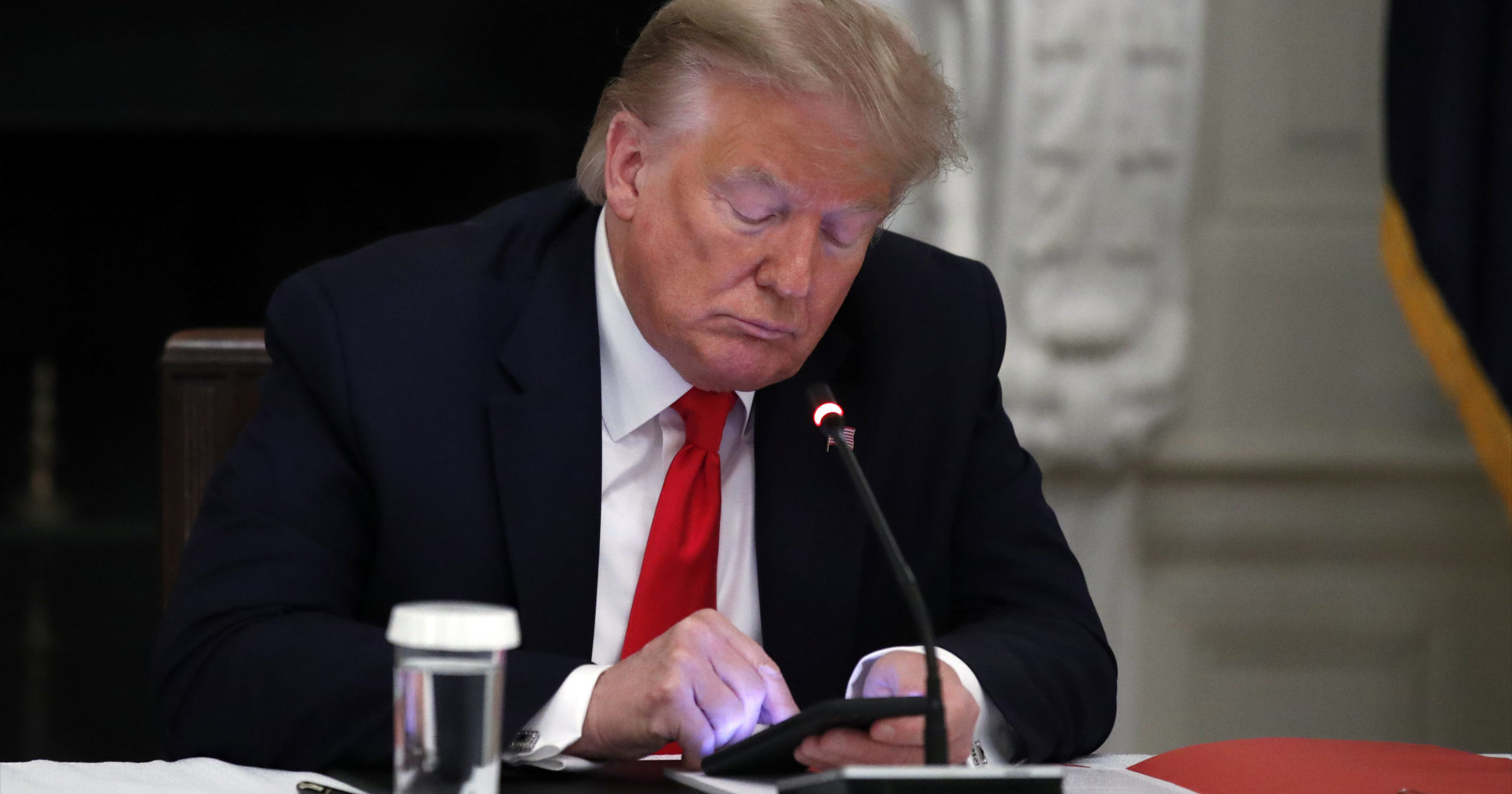 President Donald Trump looks at his phone during a roundtable with governors June 18 in the State Dining Room of the White House in Washington.