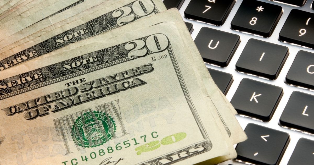 This stock photo shows a stack of $20 bills on top of a computer keyboard. The Biden administration is reportedly trying to fast-track the implementation of putting a new figure on the American $20 bill.
