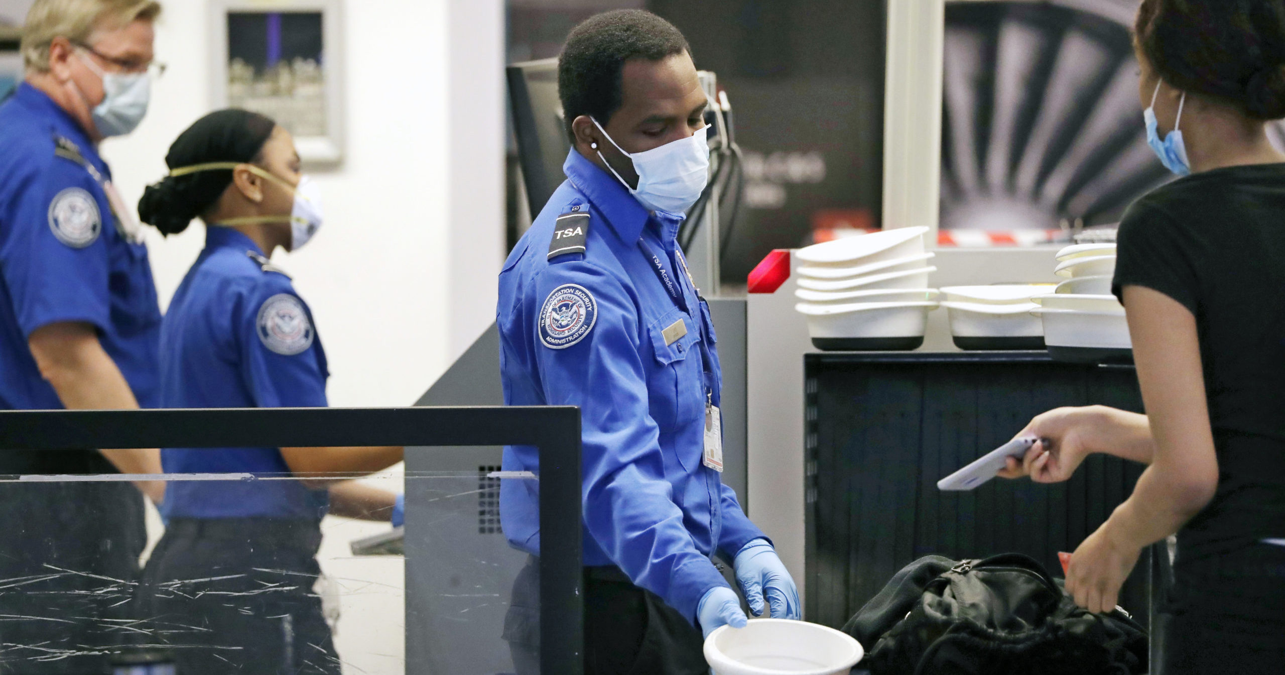 TSA officers wear protective masks at a security screening area at Seattle-Tacoma International Airport on May 18, 2020, in SeaTac, Washington.