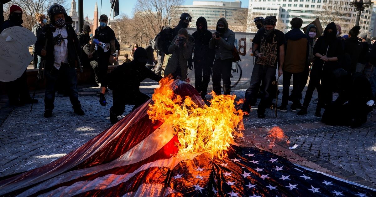 Members of antifa burn an American flag on the steps of the Colorado State Capitol on Wednesday in Denver, Colorado.