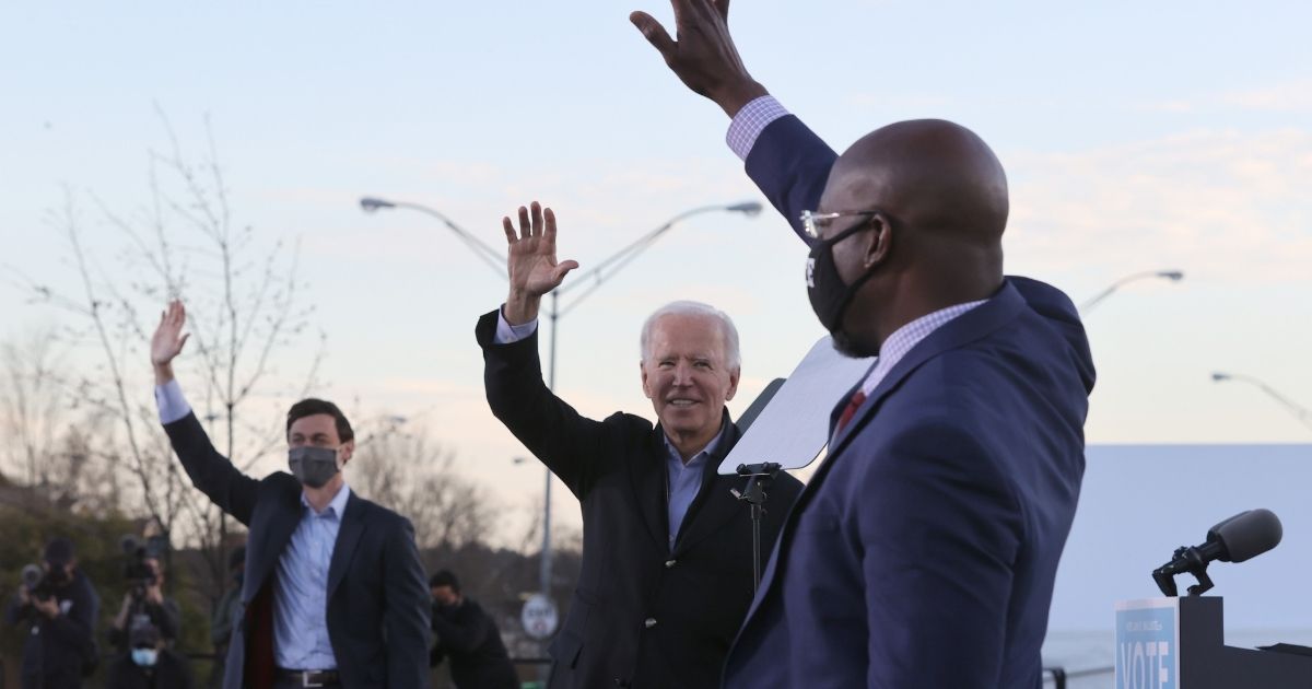 Presumptive President-elect Joe Biden campaigns with Democratic Senate candidates Jon Ossoff, left, and the Rev. Raphael Warnock in the parking lot of Center Parc Stadium in Atlanta on Monday.