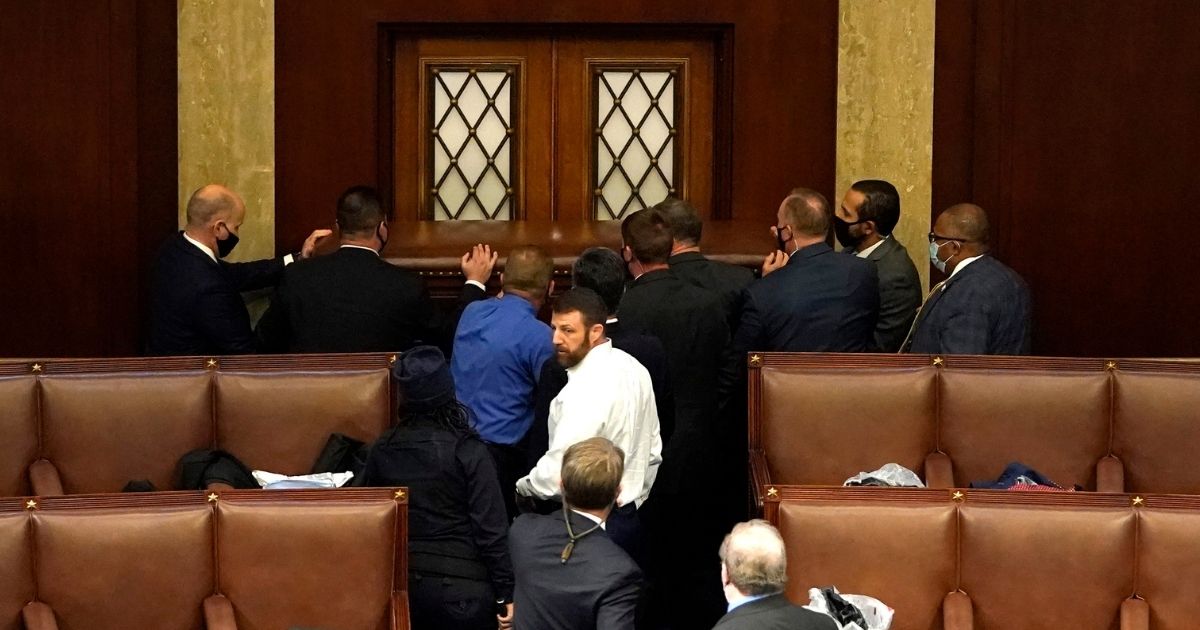 Police officers and members of Congress including Republican Rep. Markwayne Mullin of Oklahoma, center in white shirt, attempt to barricade a door that was vandalized in the House Chamber during a joint session of Congress in Washington, D.C., on Wednesday.