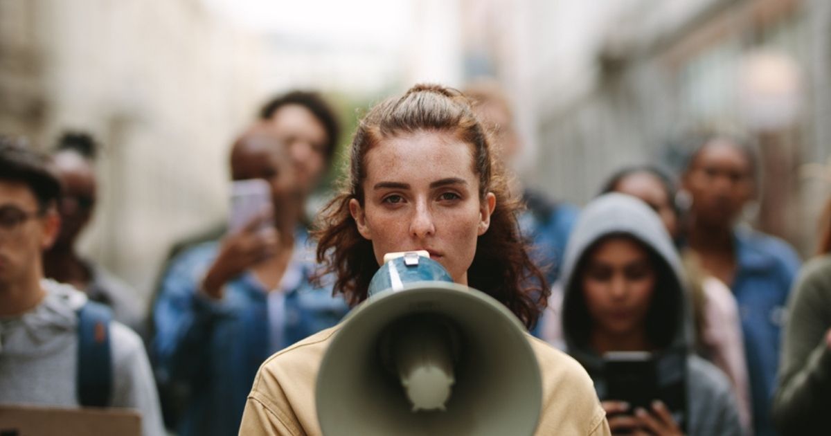 A group of demonstrators are led by a person with a megaphone in the stock image above.