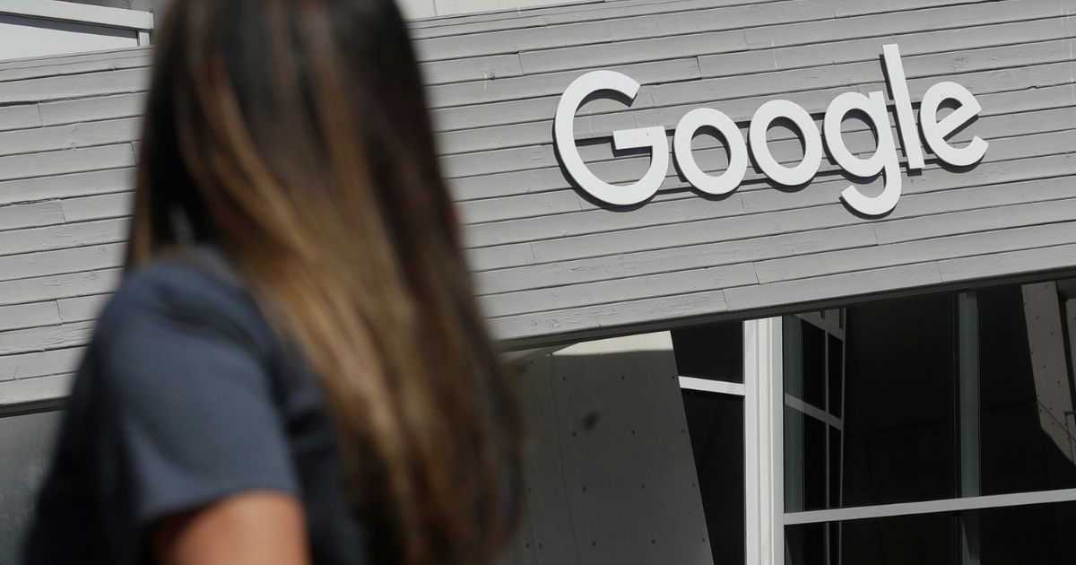 In this Sept. 24, 2019, photo a woman walks below a Google sign on the company's campus in Mountain View, California.