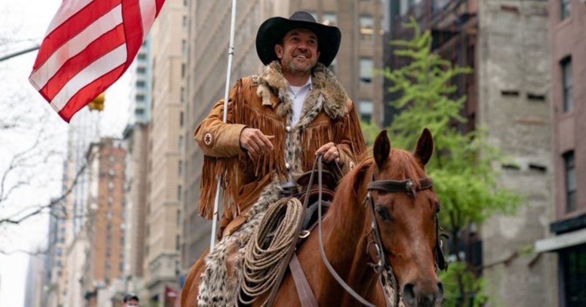 Couy Griffin, leader of Cowboys for Trump, carries an American flag on horseback.