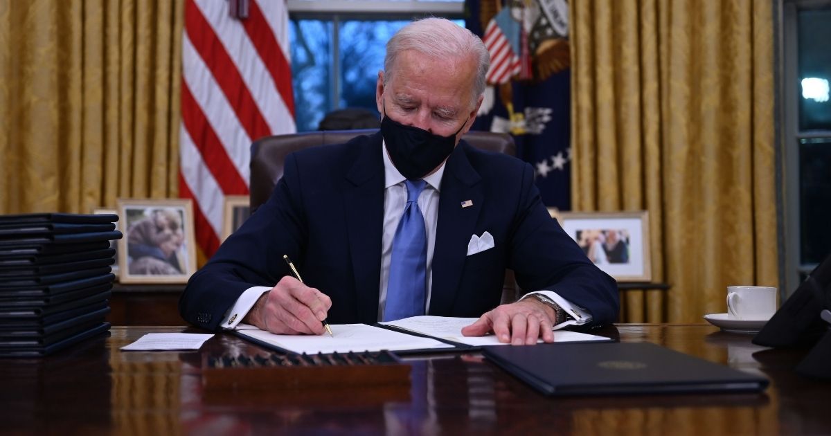 President Joe Biden signs a series of executive orders as he sits in the Oval Office of the White House in Washington after his inauguration Wednesday.