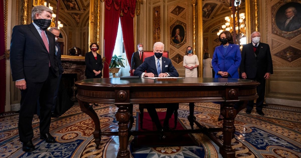 President Joe Biden signs documents as Vice President Kamala Harris, right, and others watch in the President's Room of the U.S. Capitol in Washington after Biden's inauguration ceremony Jan. 20.
