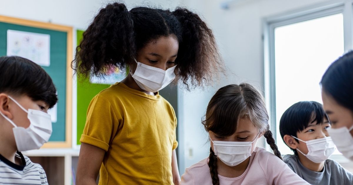 Children in a classroom wear masks while looking at school work. New research has found that there is little evidence children attending school in person has contributed to greater COVID-19 infection rates.