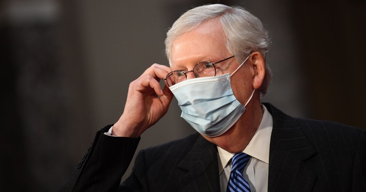 Senate Majority Leader Mitch McConnell wears a face mask as he participates in a mock swearing-in for the 117th Congress with Vice President Mike Pence in the Old Senate Chambers at the U.S. Capitol Building Sunday in Washington, D.C.