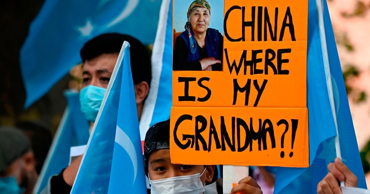 A young Uighur activist holds up a poster that reads "China where is my grandma?!"