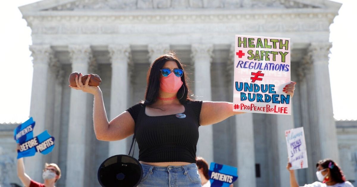Terrisa Bukovinac, founder of Pro-Life San Francisco, holds a model of a fetus as she and other anti-abortion protesters wait outside the Supreme Court for a decision, Monday, June 29, 2020.