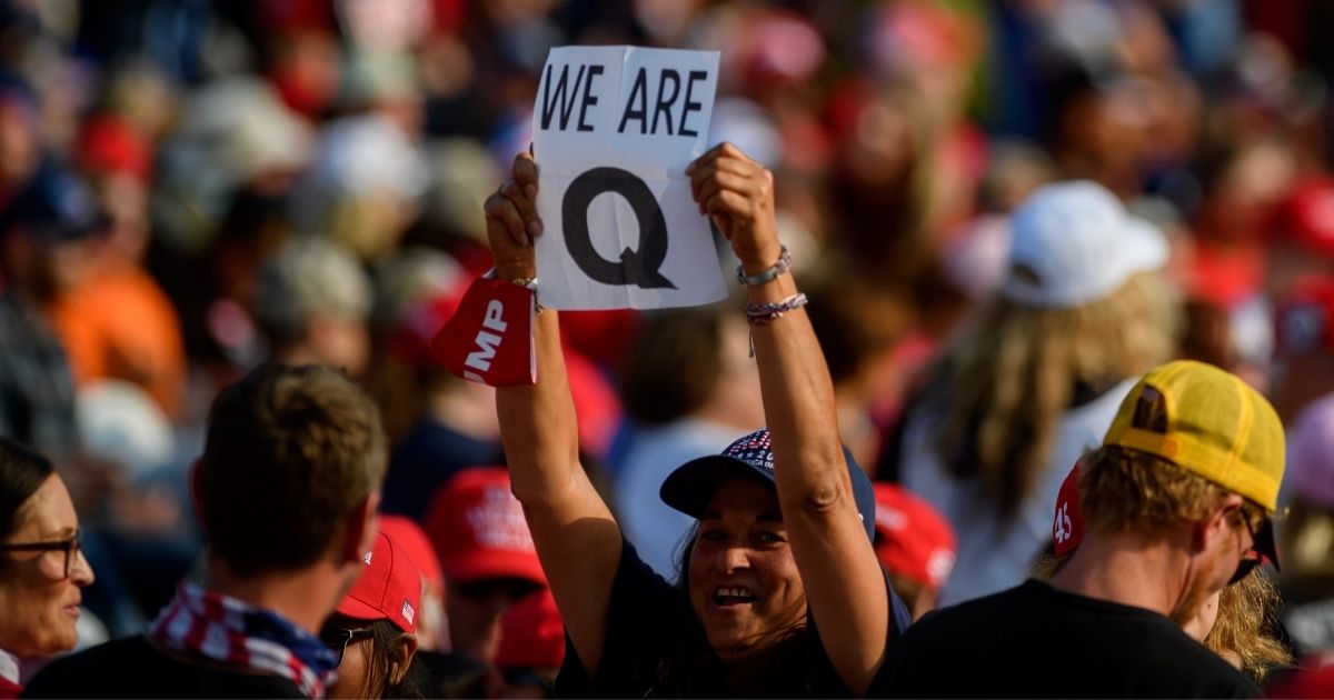 A woman holds up a QAnon sign to the media as attendees wait for President Donald Trump to speak at a campaign rally at Atlantic Aviation on Sept. 22, 2020, in Moon Township, Pennsylvania.