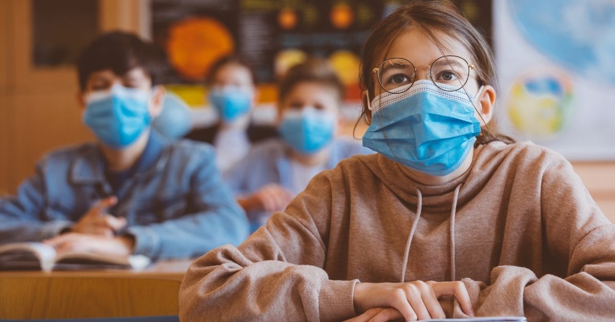 This stock photo shows students in a classroom wearing masks.