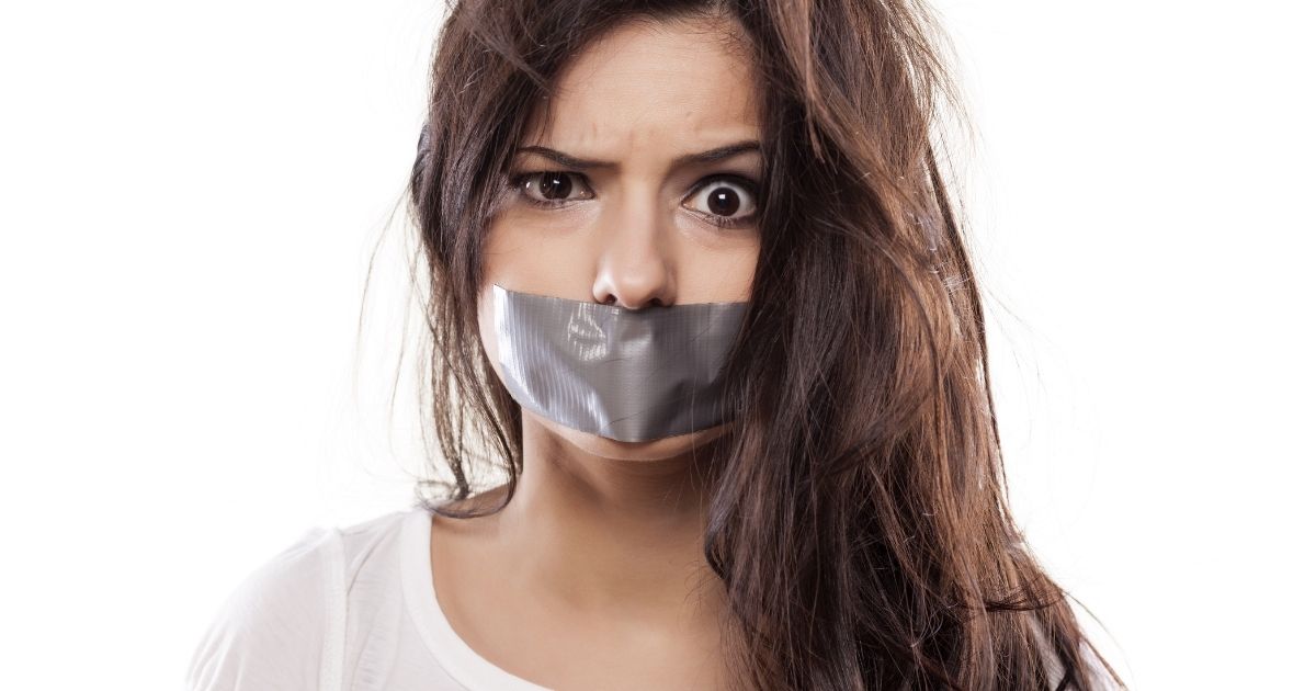 A young woman looking annoyed about the duct tape over her mouth.