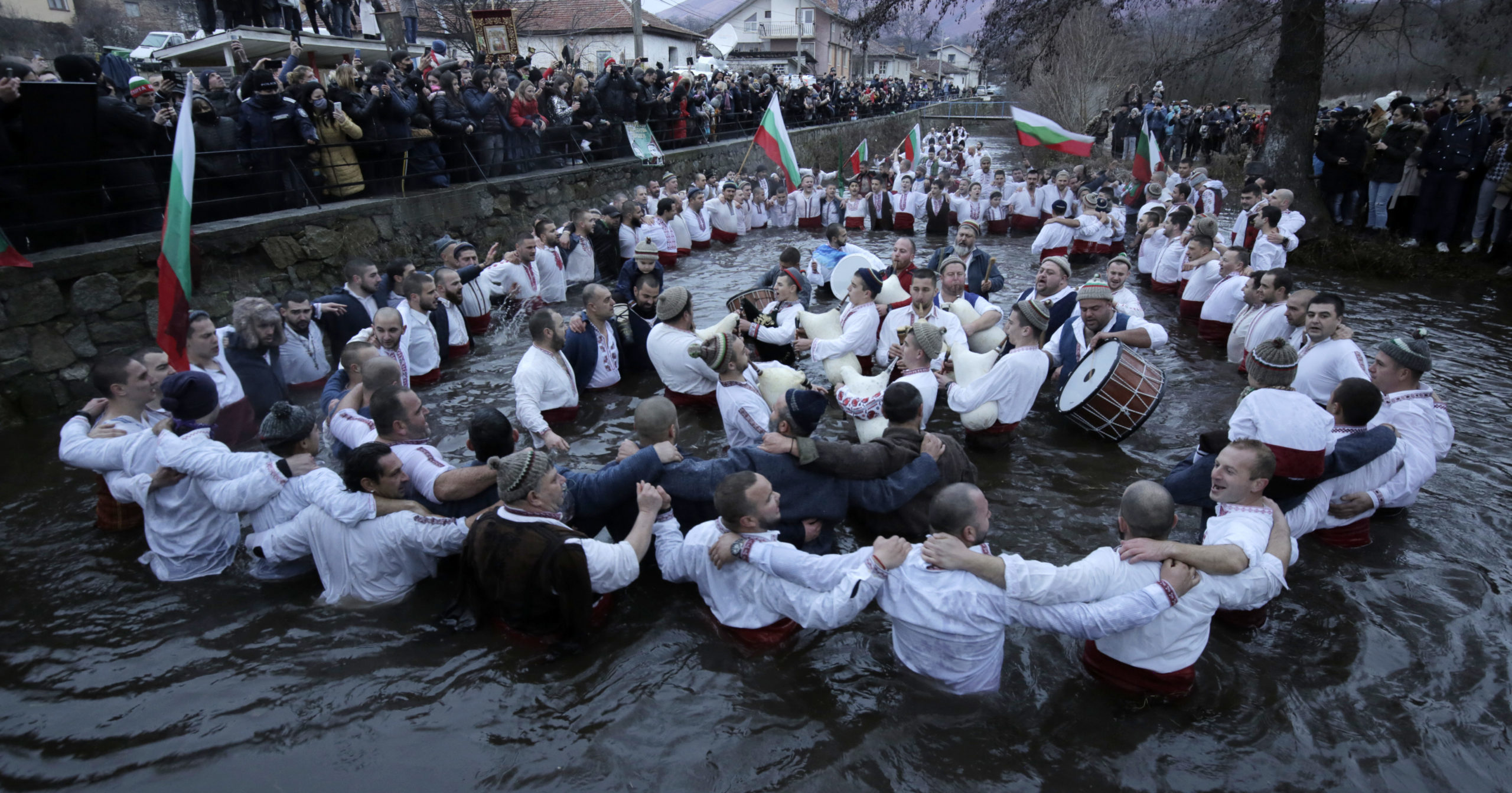 Citizens of the mountain town of Kalofer in central Bulgaria, clad in traditional garments, stand in the icy Tundzha River in an old ritual marking the feast of Epiphany on Jan. 6, 2021.