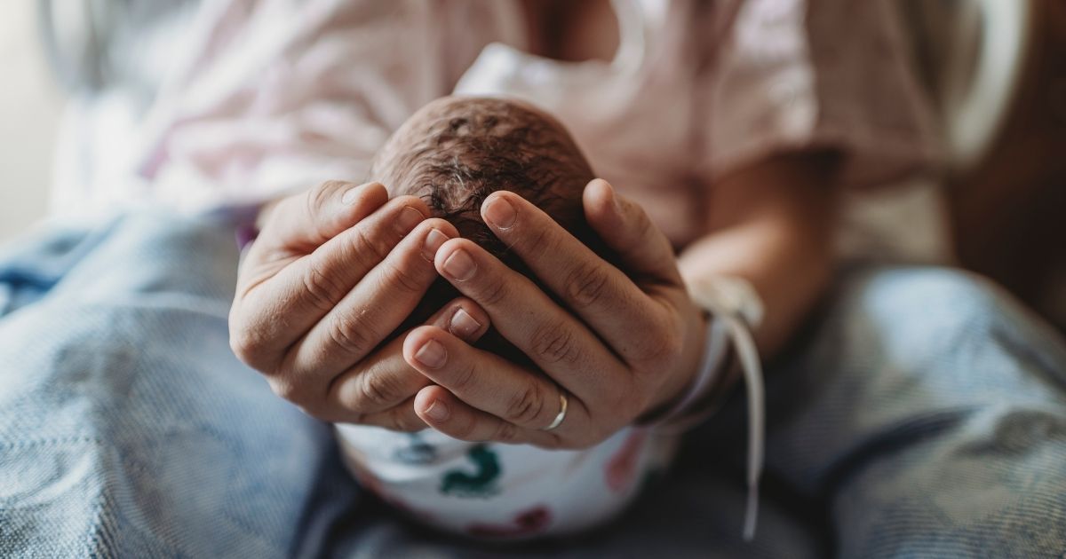 This stock image shows a mother holding a newborn baby.