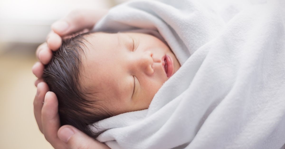 A mother holds a newborn baby in this stock image.
