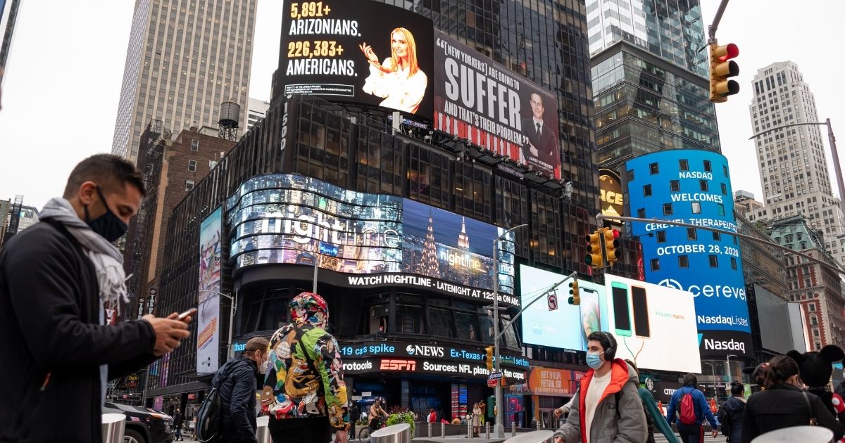 People walk by billboards by the Lincoln Project in Times Square on Oct. 28, 2020, in New York City.