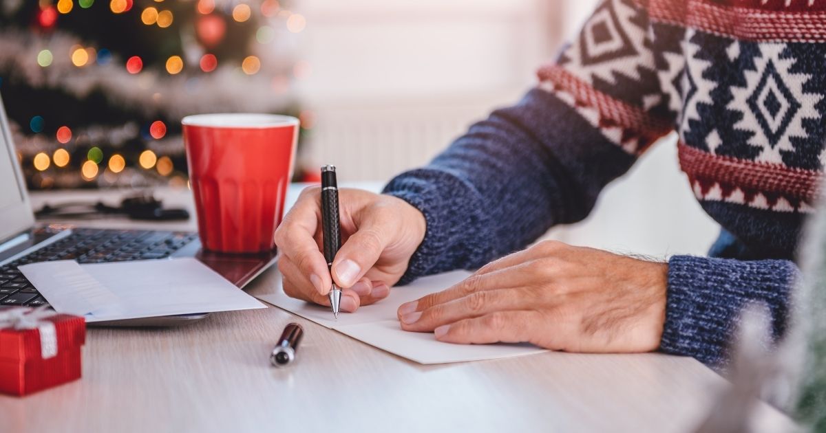 Man writing a note in a Christmas sweater