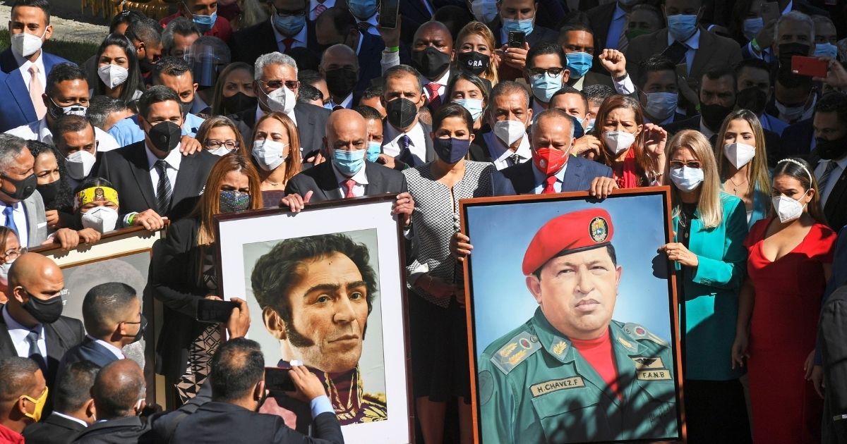 Venezuelan pro-government deputies arrive to the National Assembly building carrying portraits of Simon Bolivar, left, and the late president Hugo Chavez in Caracas on Jan. 5, 2021.