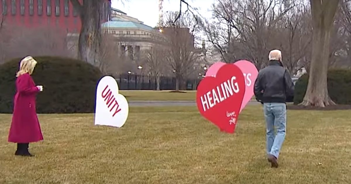 President Joe Biden and first lady Jill Biden walk among her Valentine's hearts on the White House lawn.