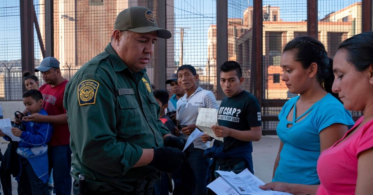 U.S. Customs and Border Protection agent checks documents of a small group of migrants, who crossed the Rio Grande from Juarez, Mexico, on May 16, 2019, in El Paso, Texas.