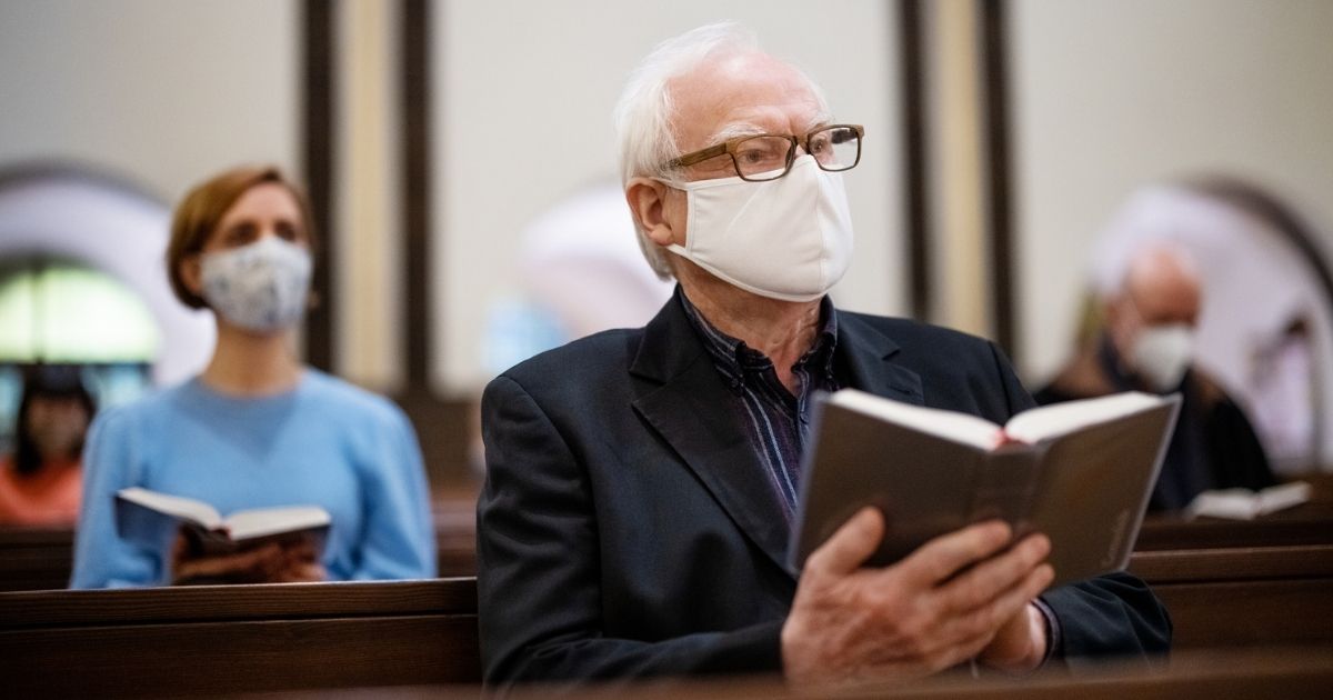The above stock photo shows a man wearing a face mask at church.
