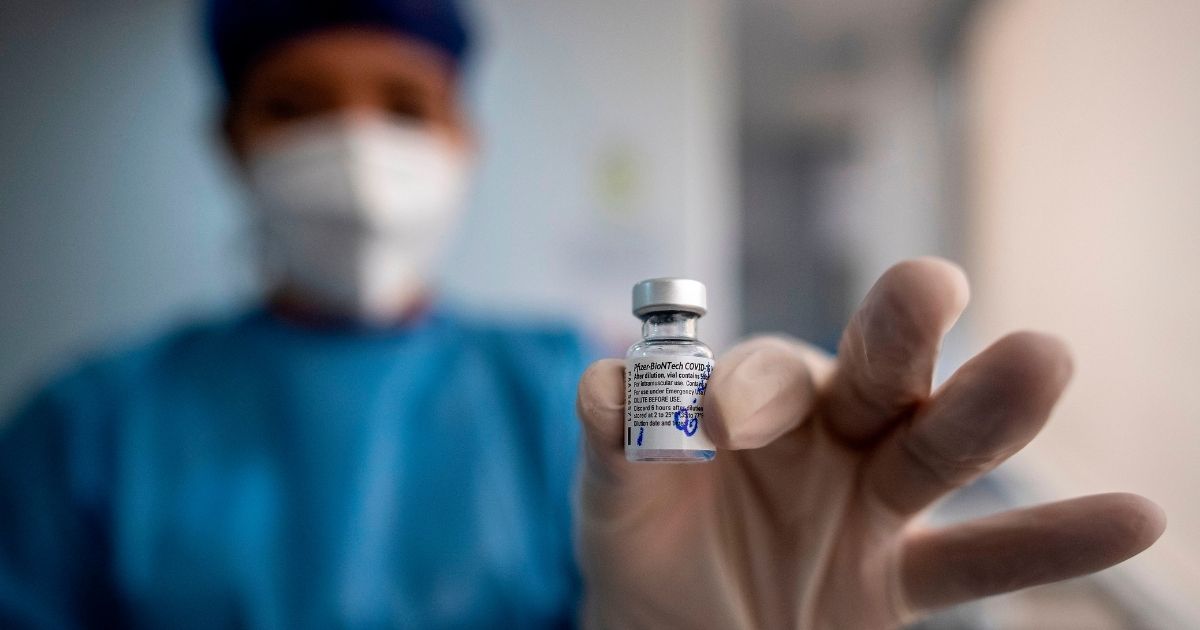 A doctor holds a vial of the Pfizer COVID vaccine