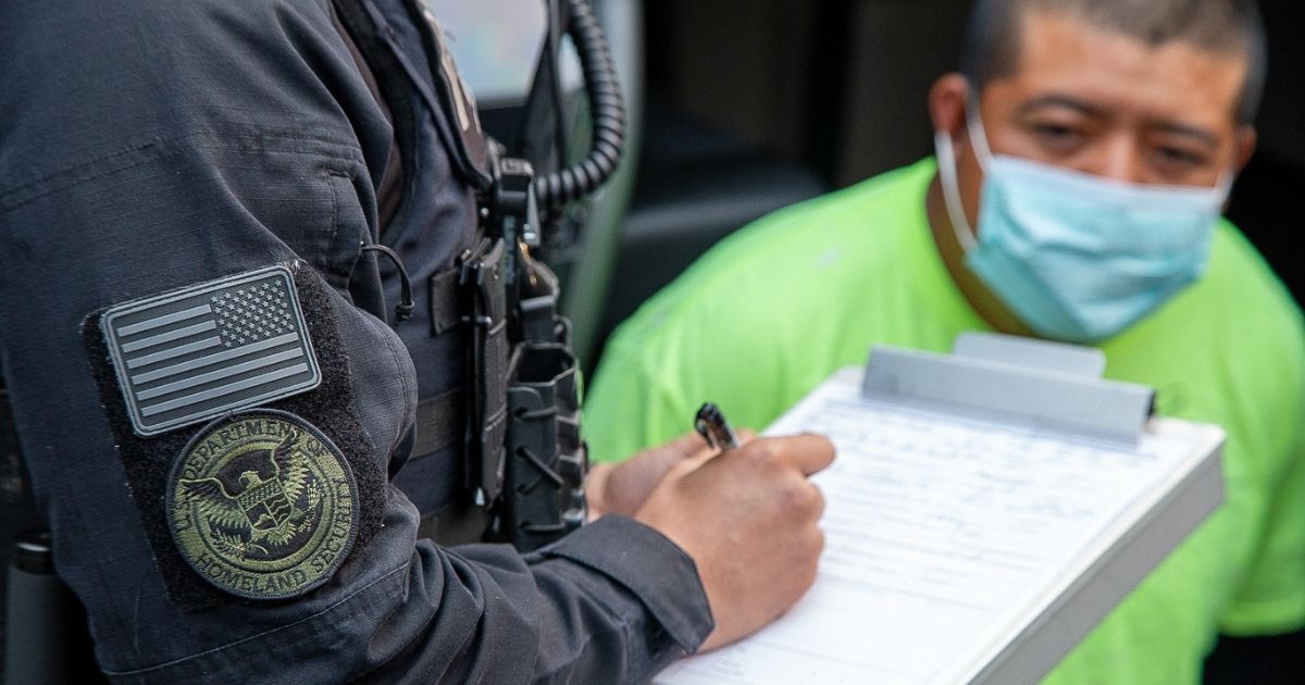 An officer with U.S. Immigration and Customs Enforcement writes a report Oct. 7 during a Trump administration effort to apprehend at-large aliens in California.