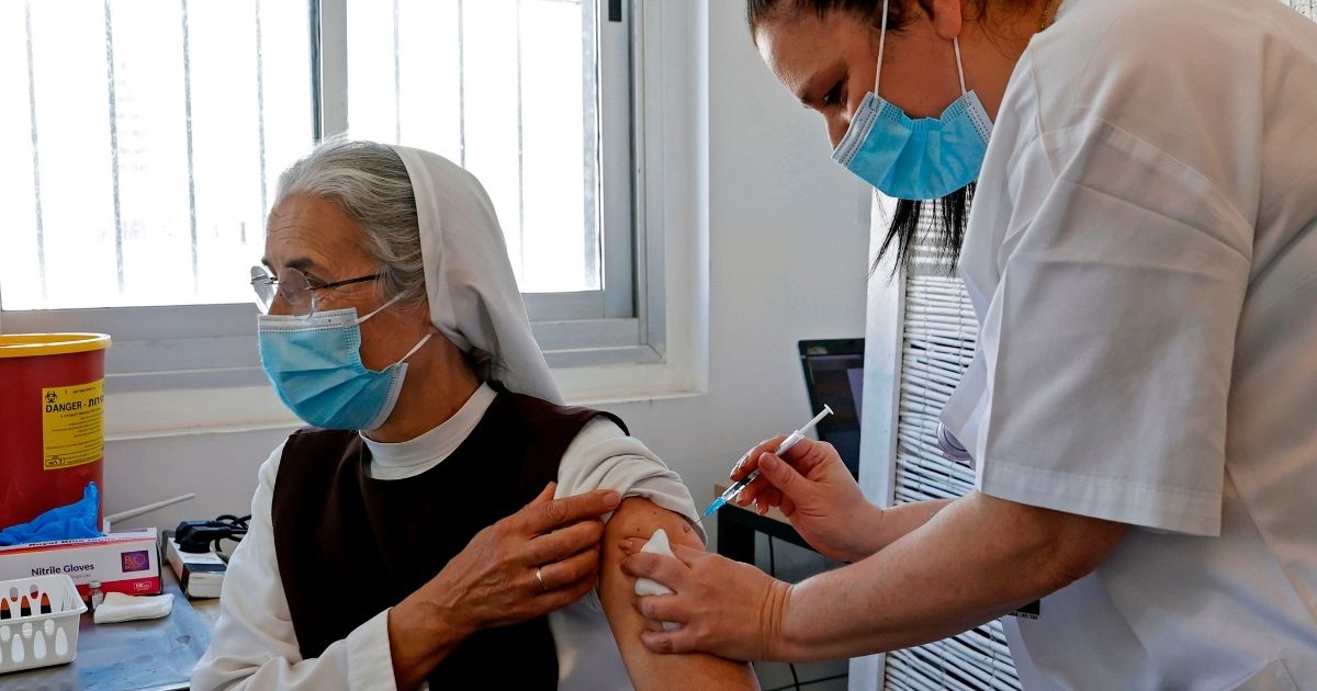 A French nun living in Israel receives a dose of the COVID-19 vaccine at the Tel Aviv Sourasky Medical Centre for foreign nationals in the Mediterranean coastal city of Tel Aviv on Tuesday during a campaign to vaccinate foreign workers and refugees against coronavirus.